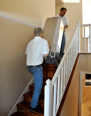 men carrying heat treatment device up stairs